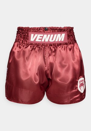 Pantaloncini sportivi in raso rosso con vita arricciata. Presentano un logo VENUM bianco sul retro e una toppa con logo sul lato. Texture liscia.