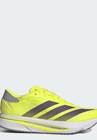 Νεον κίτρινο αθλητικό παπούτσι Adidas με μαύρες ρίγες, ανοιχτό γκρι λεπτομέρεια στη φτέρνα και λευκή σόλα με σήμανση "Lightstrike Pro."