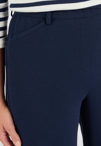 Middengrijze op maat gemaakte broek gemaakt van gestructureerde stof, met voorzakken en een rechte snit. Glad tailleband, geen zichtbare bevestigingsmiddelen.