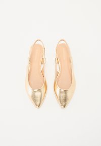 Des chaussures slingback métalliques dorées avec un bout pointu, une texture lisse et une fine sangle de talon. La semelle intérieure présente une teinte beige.
