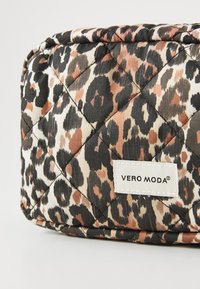 Kvadrišna kozmetička torbica s uzorkom leopardnog printa u nijansama crne, smeđe i bež. Uključuje bijelu oznaku s natpisom "VERO MODA".