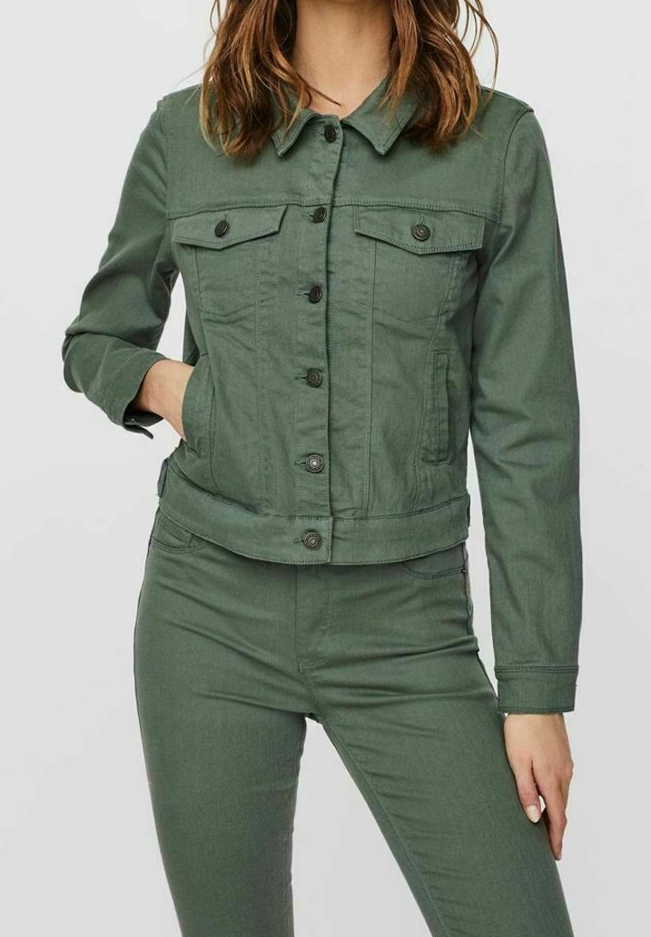 Grön denimjacka med knäppning, två bröstfickor och kortad design. Slät textur och kontrasterande svarta knappar.