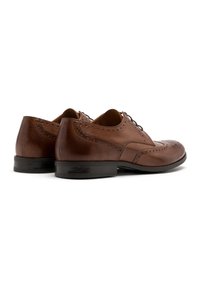 Braune Lederdressschuhe mit dekorativen Perforationen, glatter Textur, abgerundetem Zehenbereich und dünnen schwarzen Sohlen. Schnürdesign an der Oberseite.