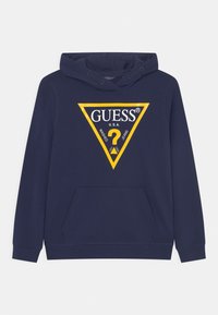 Sudadera azul marino con bolsillo frontal y logo triangular con borde amarillo que dice "GUESS U.S.A. Washed Jeans" con un signo de interrogación dentro.