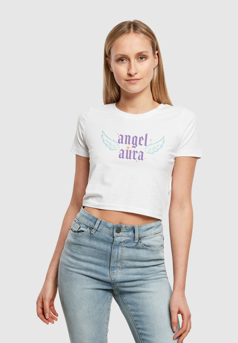 Hvit cropped t-skjorte med "angel aura" grafikk, som har lyseblå vinger og stjerner. Kombinert med lyseblå høytlivsjeans.