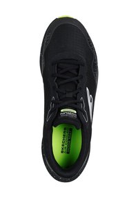 Scarpa sportiva nera con tomaia texturizzata, accenti bianchi e soletta verde neon. Presenta una punta arrotondata e suola maculata.