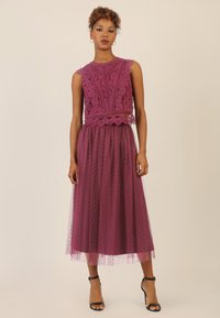 Paarse kant-top met ingewikkelde patronen, gecombineerd met een doorschijnende tule rok met stippen. Heeft een aansluitende bodice en een vloeiende zoom.