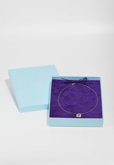 Collana d'oro con un pendente quadrato esposta in una scatola blu chiaro foderata di velluto viola e legata con un nastro coordinato.