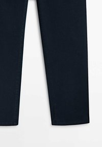 Vue sur la longueur de jambe d'un pantalon noir slim-fit avec des ourlets nets sur fond blanc.