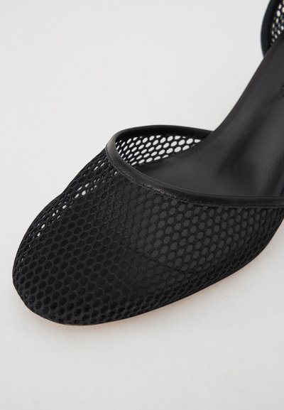Black mesh high-heeled shoe with a pointed toe and open design, featuring a smooth black trim and textured breathable material.