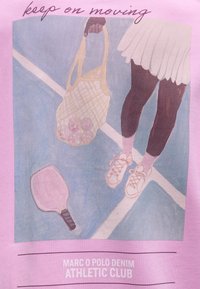 Πόδια σε τένις σύνολο που κρατούν δίχτυ με μπάλες τένις, ρακέτα στο γήπεδο, κείμενο «συνέχισε να κινείσαι» και «Marc O Polo Denim Athletic Club.»