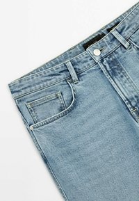 Jean en denim bleu clair avec poche avant, passants de ceinture et fermeture à bouton sur fond blanc.