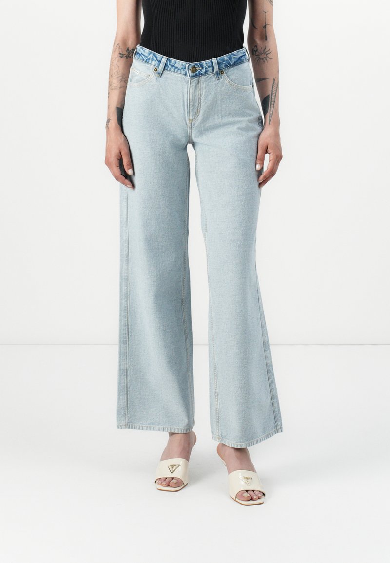 Light blue wide-leg jeans made of denim, featuring a blue patterned waistband and front pockets. Smooth texture with visible stitching details.