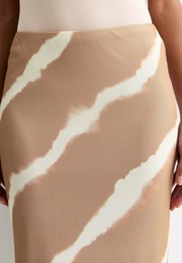 Falda lápiz en tela beige con un patrón abstracto de rayas blancas y marrón claro. Textura suave y diseño ajustado que realza la cintura.