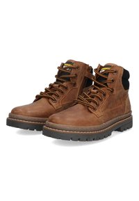 Bruine leren veterschoenen voor werk met zwarte gevoerde kraag, zijritsen en dikke profielzolen, weergegeven tegen een witte achtergrond.