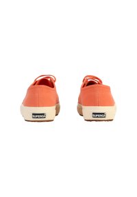Zapatillas de lona naranjas con suela de goma, que presentan una parte trasera redondeada, una pestaña en el talón para ayudar a ponérselas y un logo visible en el talón.