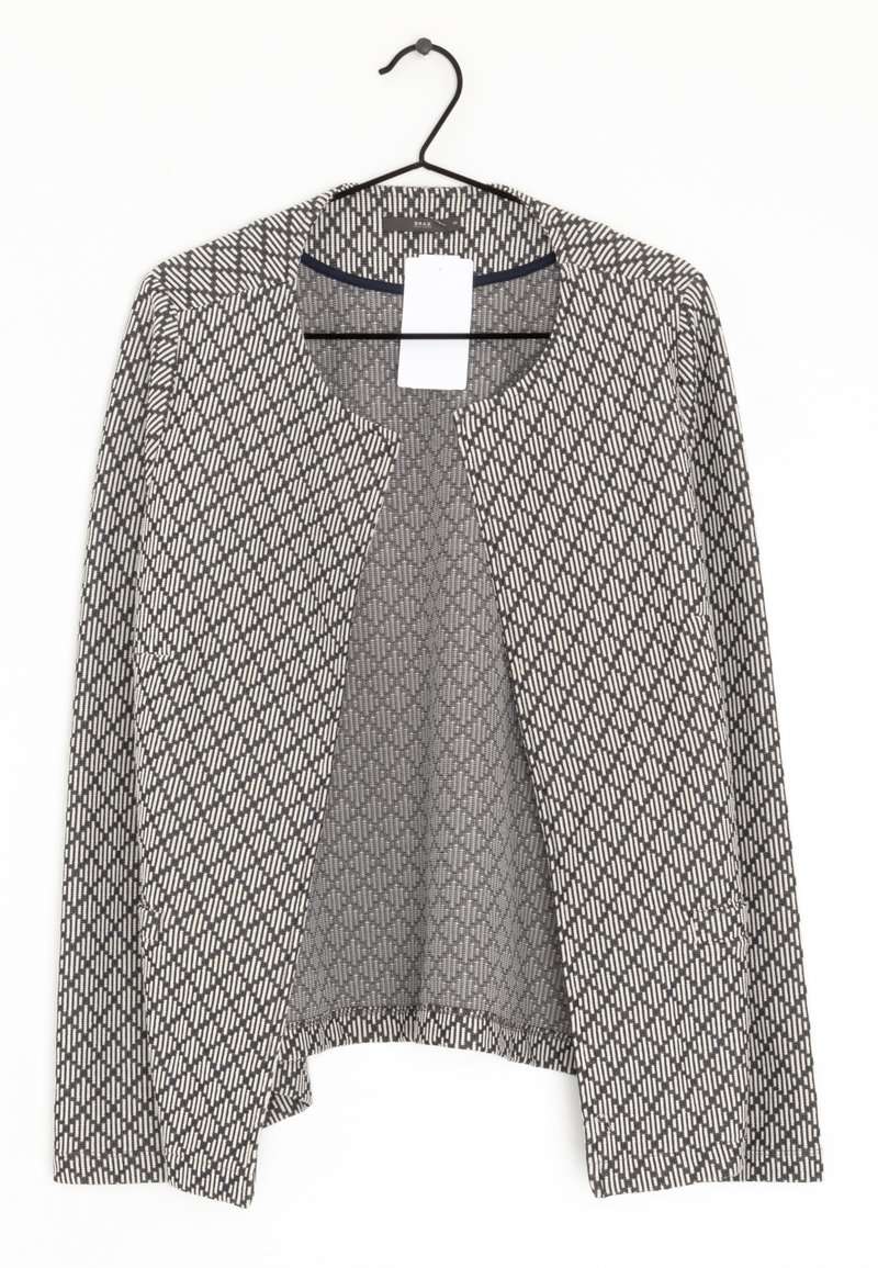 Cardigan à manches longues à motifs noir et blanc, ouvert devant, accroché à un cintre noir avec une étiquette de prix blanche visible.