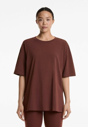 T-shirt rouge bordeaux surdimensionné en tissu doux et respirant. Il présente un col rond et des manches courtes, avec une coupe décontractée et droite.