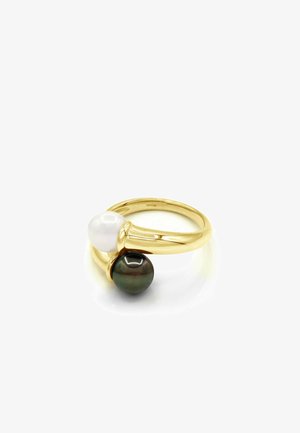 Bague en or ornée de deux perles, une blanche et une foncée, placées face à face sur un fond blanc uni.