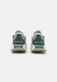 Bežecké topánky GORE-TEX s šedou a tyrkysovou sieťovinou, pevným tyrkysovým akcentom a polstrovanou bielou a svetlozelenou podrážkou.
