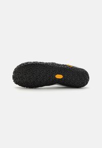 Semelle de chaussure en caoutchouc noir avec motif de semelle texturé. Présente un accent de logo jaune. La forme générale est conçue pour l'adhérence et la stabilité.