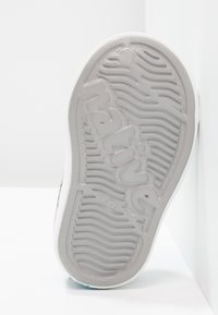 Suela de zapato de goma gris texturizada, con patrones ondulados y la palabra "native" en relieve. Laterales blancos y acentos azules visibles.