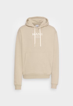 Beige hættetrøje lavet af blødt stof, med en frontlomme, snøre ved hætten og hvidt logo-tekst midt på brystet.