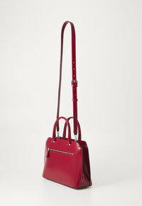 Borsa a mano in pelle verniciata rossa con doppi manici superiori e una tracolla regolabile. Presenta una tasca frontale con zip e un design strutturato.