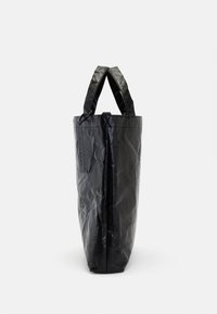 Black tote bag made of textured material with a crinkled finish. Features two handles and a top closure for secure carrying.