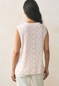 Ujjatlan felső kerek nyakkivágással, geometriai mintával rózsaszín és bézs tónusokban, könnyű anyagból készült, laza fazonban.