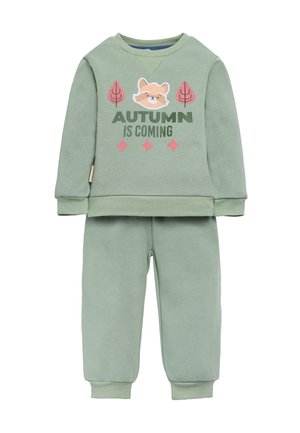 Sudadera de algodón verde y pantalones de chándal a juego. La sudadera presenta una cara de zorro de aplique y el texto "LA OTOÑO SE ACERCA" con acentos rosados.