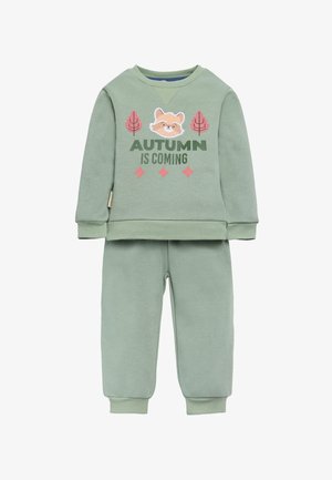 Sudadera de algodón verde y pantalones de chándal a juego. La sudadera presenta una cara de zorro de aplique y el texto "LA OTOÑO SE ACERCA" con acentos rosados.