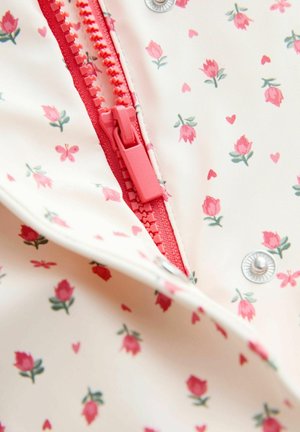 Roosa luku ja pressnööp kreemja kangal, millel on mustriks väikesed roosad lilleõied, südamed ja liblikad.