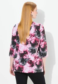 Halenka s květinovým vzorem v růžové, černé a šedé barvě, se třičtvrtinovými rukávy a zaobleným lemem. Měkká tkanina s hladkým povrchem.
