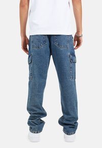 Pantaloni cargo in denim blu, larghi, con tasche laterali, cuciture rinforzate e fit rilassato. Tasche posteriori a toppa visibili e orli con risvolto.