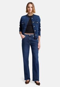 Granatowa kurtka dżinsowa z dwoma kieszeniami na klatce piersiowej i srebrnymi guzikami, zestawiona z granatowymi spodniami w dzwony i brązowymi balerinami w zwierzęcy wzór.