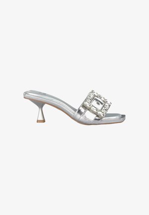 Zilveren sandalen met hakken, voorzien van een brede strap met heldere edelstenen en een conische hak. Gladde metallic afwerking met een platte zool.