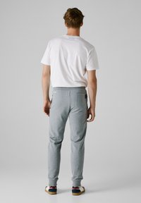 Pánska biela košeľa s krátkym rukávom s logom "Pepe Jeans", kombinovaná so sivými teplákmi so slim fit strihom a elastickými manžetami.