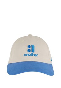 Cappello da baseball in cotone beige con visiera blu. Presenta il testo ricamato "another" e una grafica in blu abbinato. Dettagli di cucitura sottili.