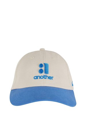 Baseball cap in beige cotton with a blue visor. Features embroidered text "another" and a graphic in matching blue. Subtle stitching details.