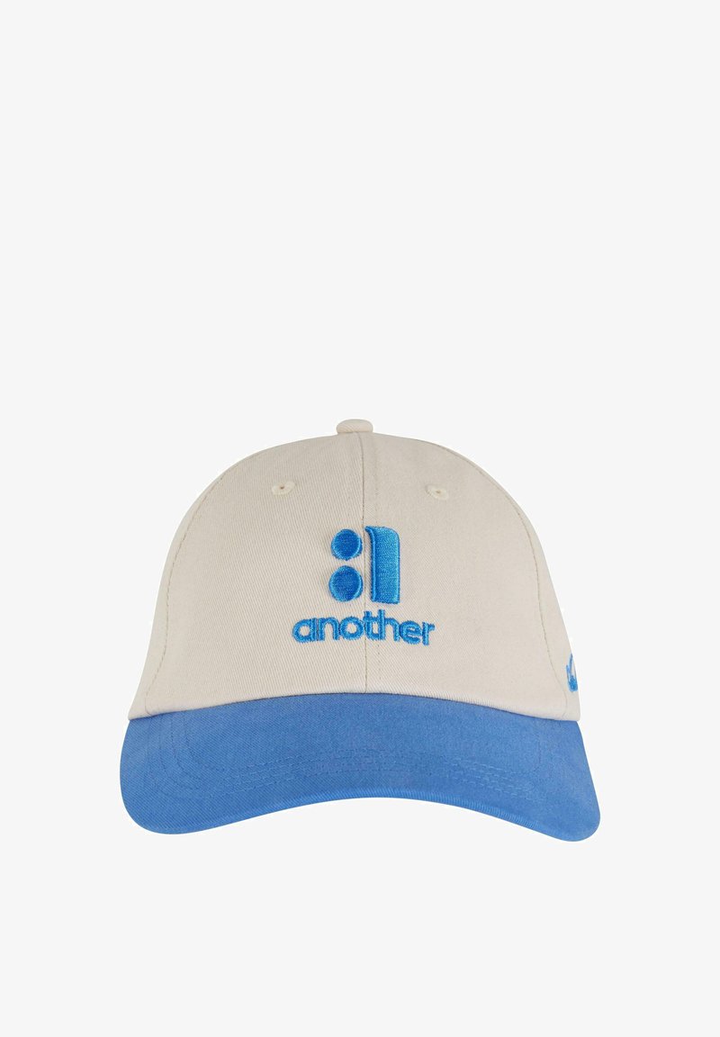 Beige kokvilnas cepure ar zilu vizieri. Iekļauj izšūtus tekstus "cits" un grafiku atbilstošā zilos toņos. Smalks izšūšanas dizains.