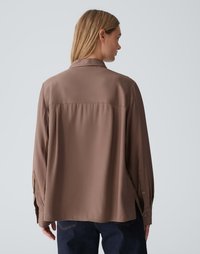 Bruine, lang opgescheurde blouse met een kraag, losse pasvorm en knoopmanchetten, gemaakt van een gladde stof. Achteraanzicht toont een middellange snit.