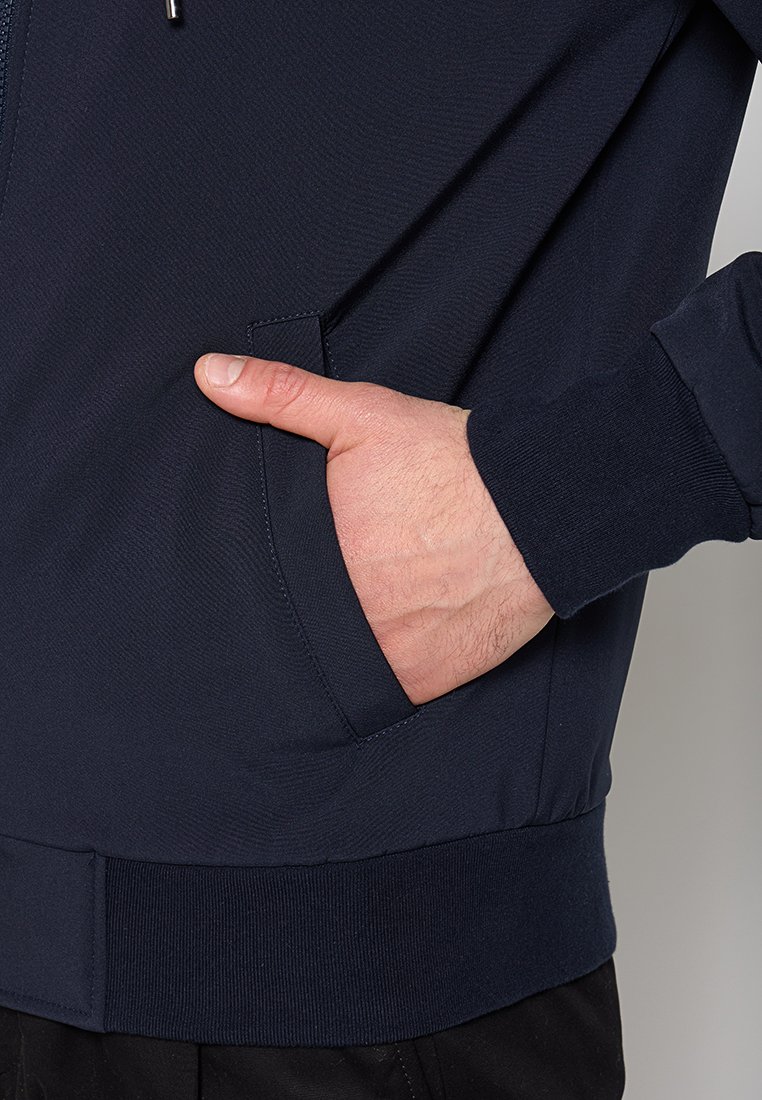 Felpa navale con zip, tasca anteriore a marsupio, polsini e orlo a coste. Caratterizzata da una texture del tessuto liscia e un design aderente.