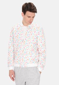 Luchtige bomberjack met een witte achtergrond, versierd met een kleurig, abstract bladerenpatroon. Geribde manchetten en zoom voor een perfecte pasvorm.