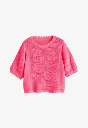Jersey rosa de crochet de manga corta con patrones florales, bordes festoneados en las mangas y el dobladillo, y un escote redondo.