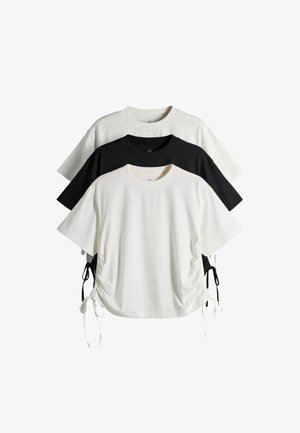 Drei kurzärmelige Rundhals-T-Shirts in Weiß, Schwarz und Hellgrau, mit seitlichen gerafften Kordeln an den weißen und schwarzen Shirts.