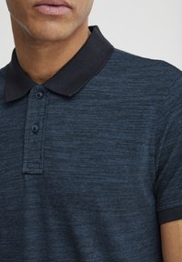 Dunkelblaue Poloshirt mit strukturiertem Finish, schwarzem Kragen, zwei Knopfverschluss und kurzen Ärmeln.