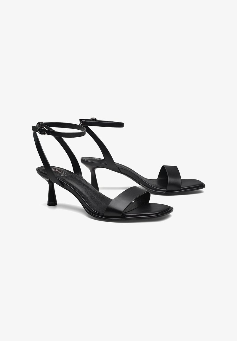 Čierne sandále na opätku s minimalistickým dizajnom, s tenkými popruhmi okolo členka, otvorenou špičkou a hladkým koženým materiálom. Výška opätku 7,5 cm.
