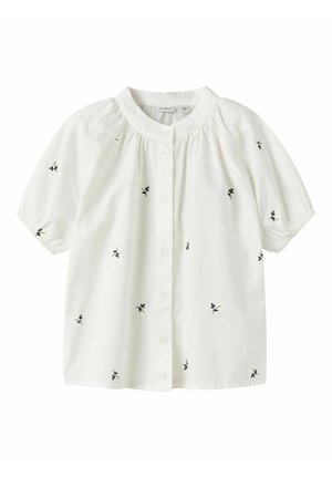 Biela blúzka s krátkym rukávom a okrúhlym golierom, zapínanie na gombíky vpredu, jemná čierno-žltá kvetinová výšivka rozptýlená po látke.