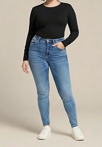 Black long-sleeve top paired with light blue skinny jeans. Jeans feature a faded wash and a five-pocket design. White slip-on shoes complete the look.